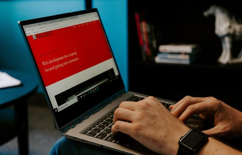 Developer typing on a laptop showing a web development website