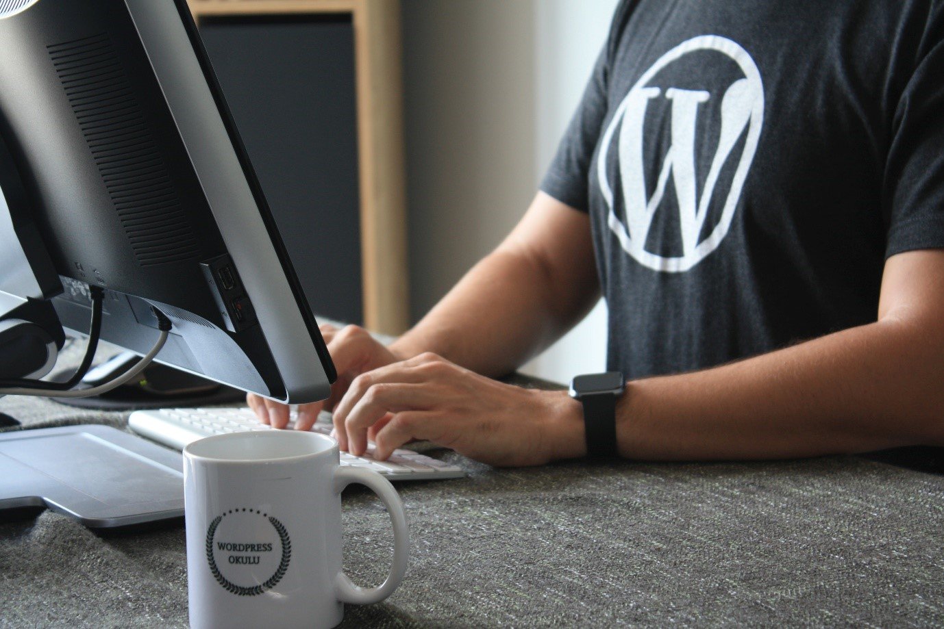 A developer in a WordPress T-shirt working at a desktop computer